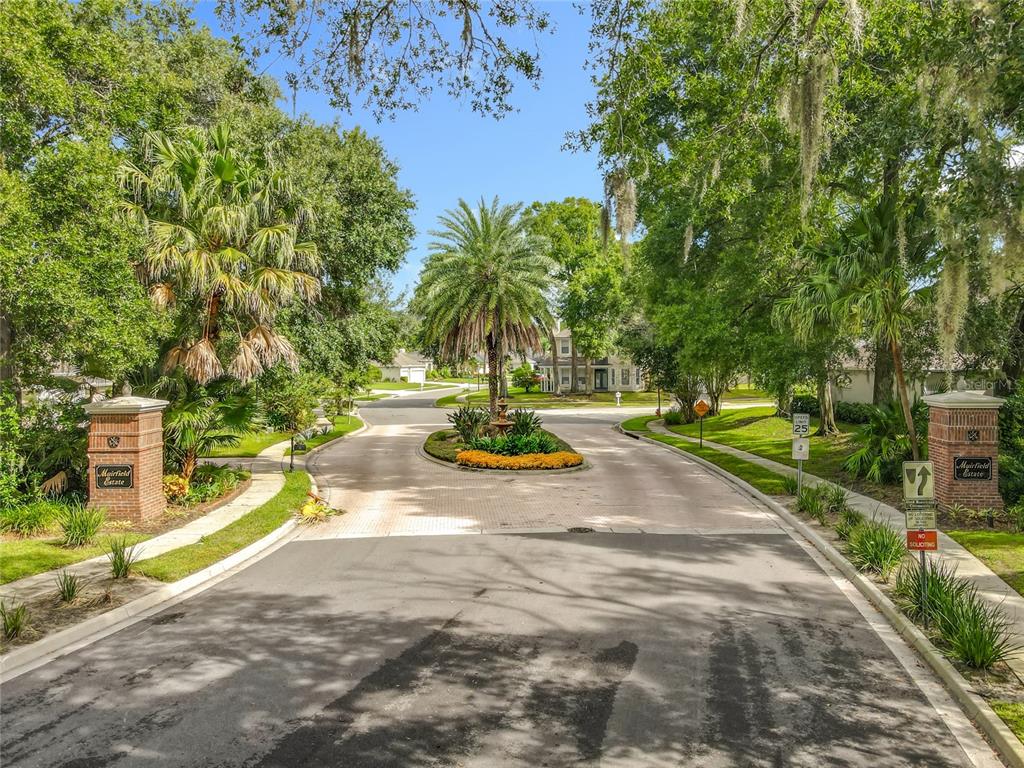 The entrance to Muirfield Estate features a brick-columned gate and a central landscaped traffic circle — 809 MUIRFIELD CIRCLE, APOPKA, FL
