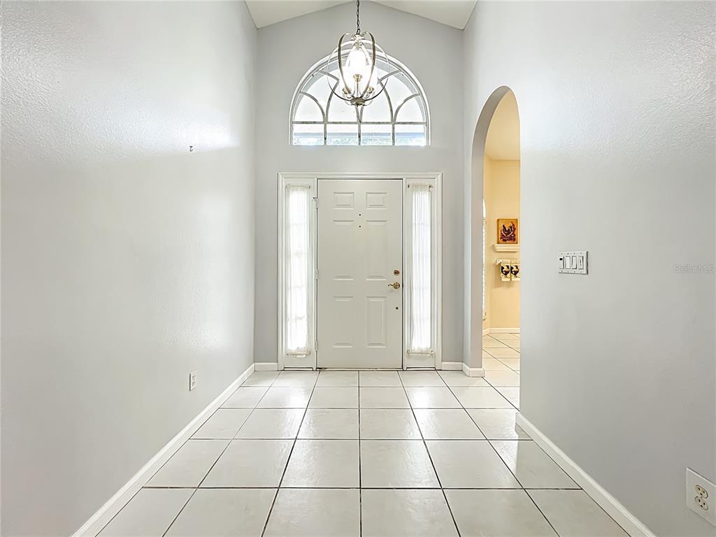 A bright entryway features white tile flooring, a vaulted ceiling, and a central arched window — 809 MUIRFIELD CIRCLE, APOPKA, FL