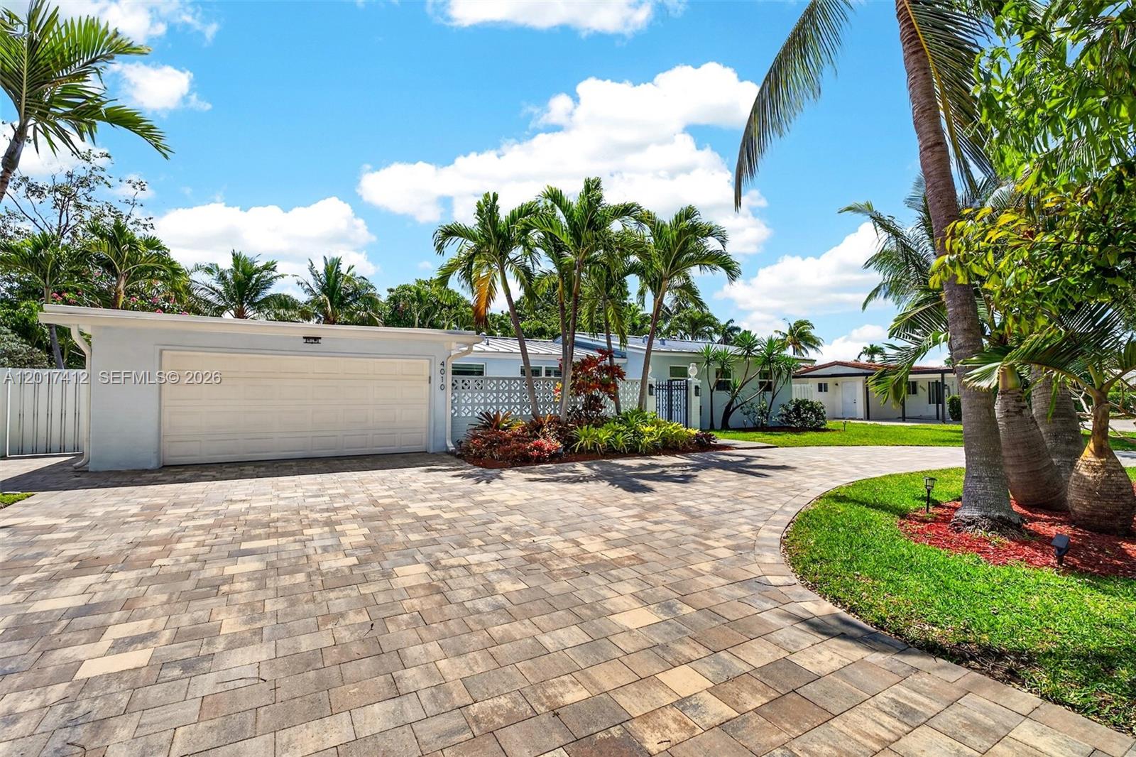 A single-story house with a paved driveway, palm trees, and a white garage door — 4010 NE 22nd Ave, Lighthouse Point FL 33064, LIGHTHOUSE POINT, FL