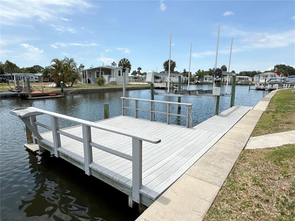 A wooden dock with railings extends into a canal in front of several mobile homes — 6806 MOUNT QUINCY DRIVE NE UNIT 361, ST PETERSBURG, FL