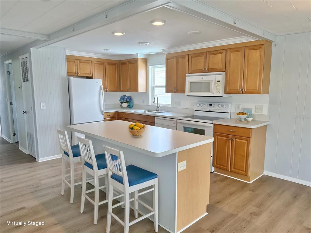 A kitchen features light wood cabinets, a central island with bar stools, and white appliances — 6806 MOUNT QUINCY DRIVE NE UNIT 361, ST PETERSBURG, FL