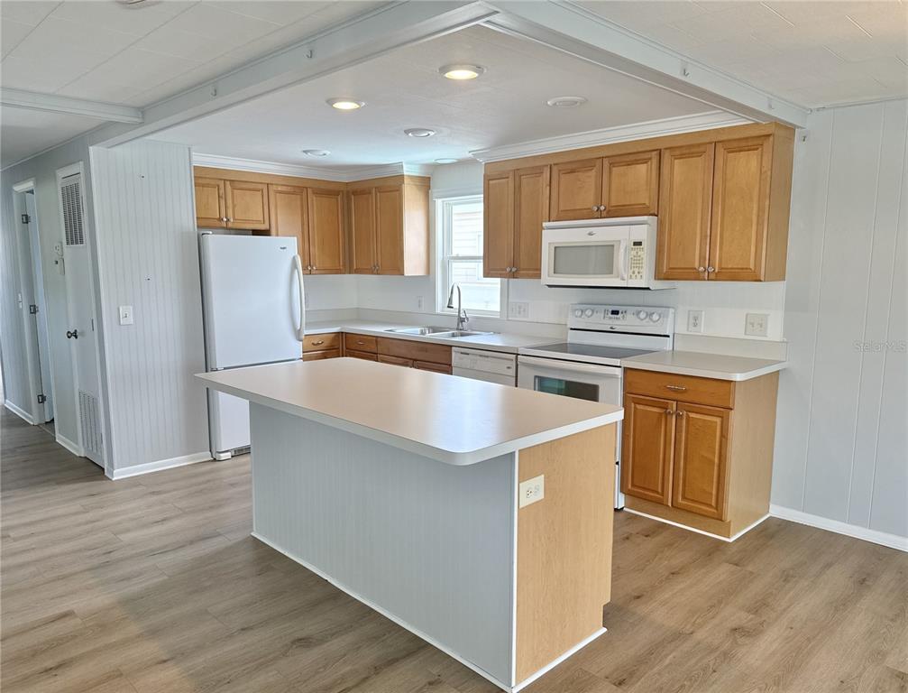 A kitchen features light wood cabinets, white appliances, a center island, and wood-look flooring — 6806 MOUNT QUINCY DRIVE NE UNIT 361, ST PETERSBURG, FL