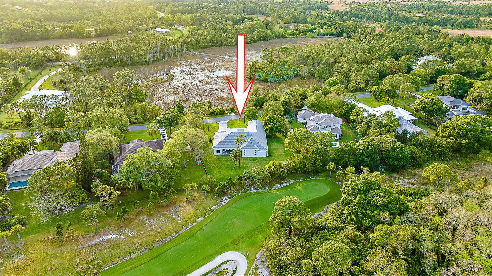 An aerial view shows a single-story house with a gray roof situated near a golf course — 18211 SE Old Trail Drive W, Jupiter FL 33478, JUPITER, FL