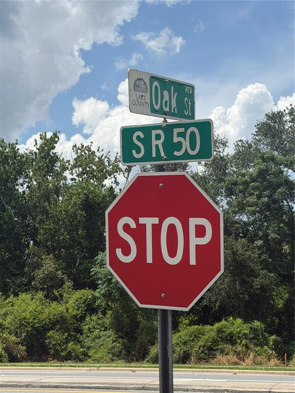 A stop sign is mounted on a pole below street signs for Oak St and SR 50 — 14435 OAK STREET, GROVELAND, FL