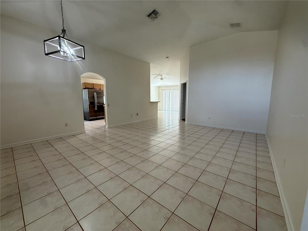 An open-concept living area features light-colored tile flooring, vaulted ceilings, and a modern pendant light — 1905 PINE BAY DRIVE, LAKE MARY, FL