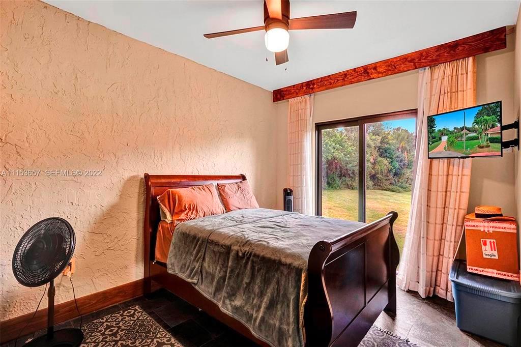A bedroom features a wooden bed, a ceiling fan, and a sliding glass door — 4808 Queen Palm Lane, Tamarac FL 33319, TAMARAC, FL