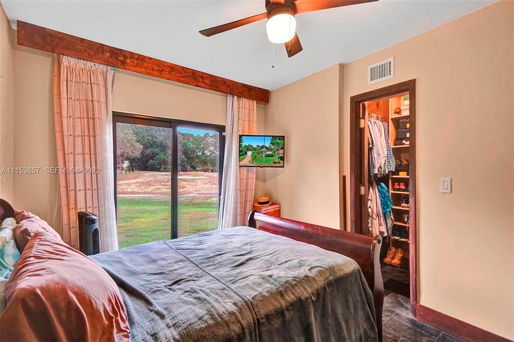 A bedroom features a wooden bed frame, a ceiling fan, and a walk-in closet — 4808 Queen Palm Lane, Tamarac FL 33319, TAMARAC, FL