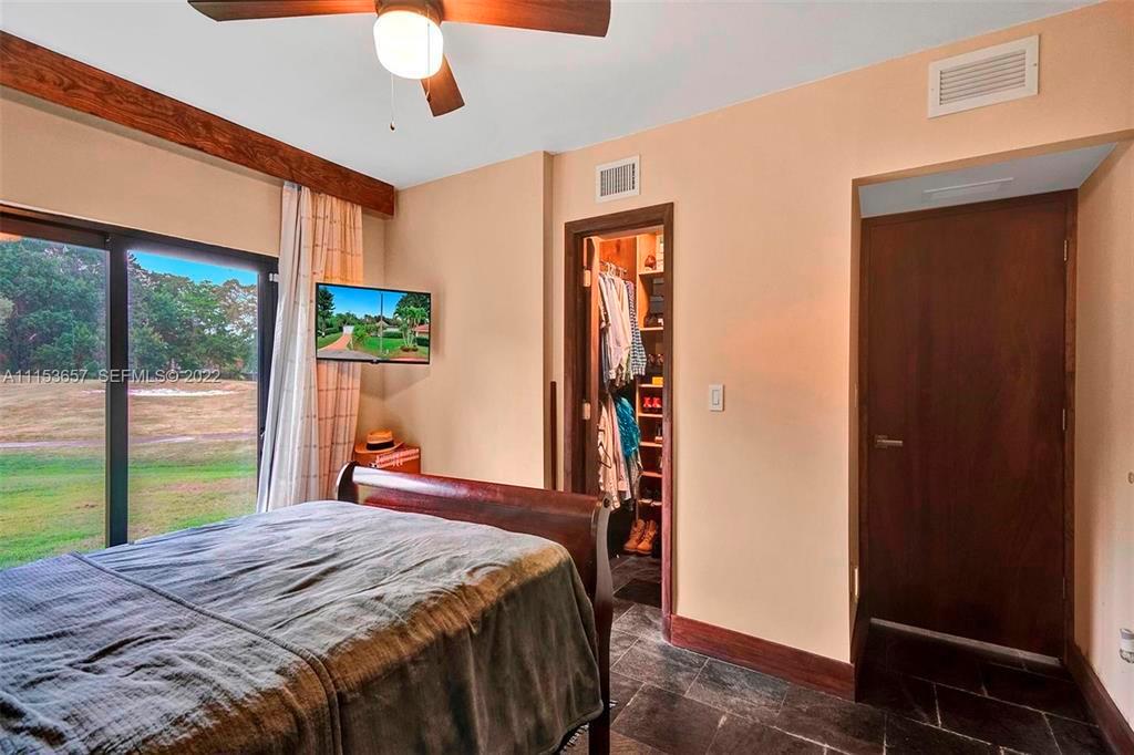 A bedroom features a dark wood bed, tile flooring, a walk-in closet, and sliding glass doors — 4808 Queen Palm Lane, Tamarac FL 33319, TAMARAC, FL
