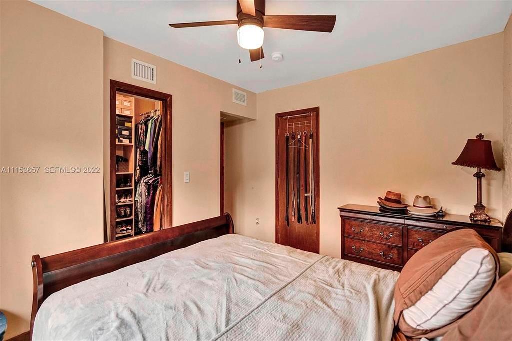 A bedroom features a wooden bed frame, a dresser with hats, and two closet doors — 4808 Queen Palm Lane, Tamarac FL 33319, TAMARAC, FL