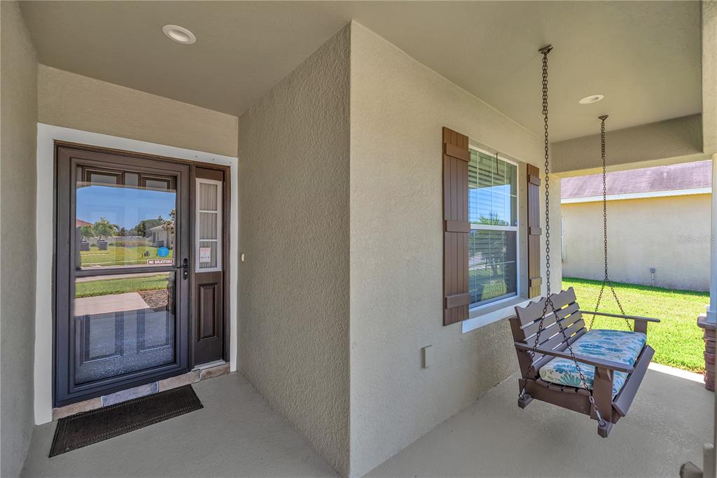 A covered front porch features a hanging wooden swing, a storm door, and a window — 5018 33RD AVENUE E, PALMETTO, FL