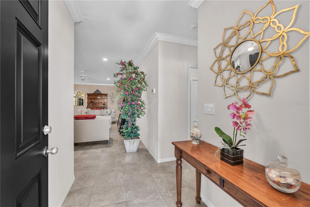 An entryway features tile flooring, a wooden console table, a decorative mirror, and a potted plant — 5018 33RD AVENUE E, PALMETTO, FL