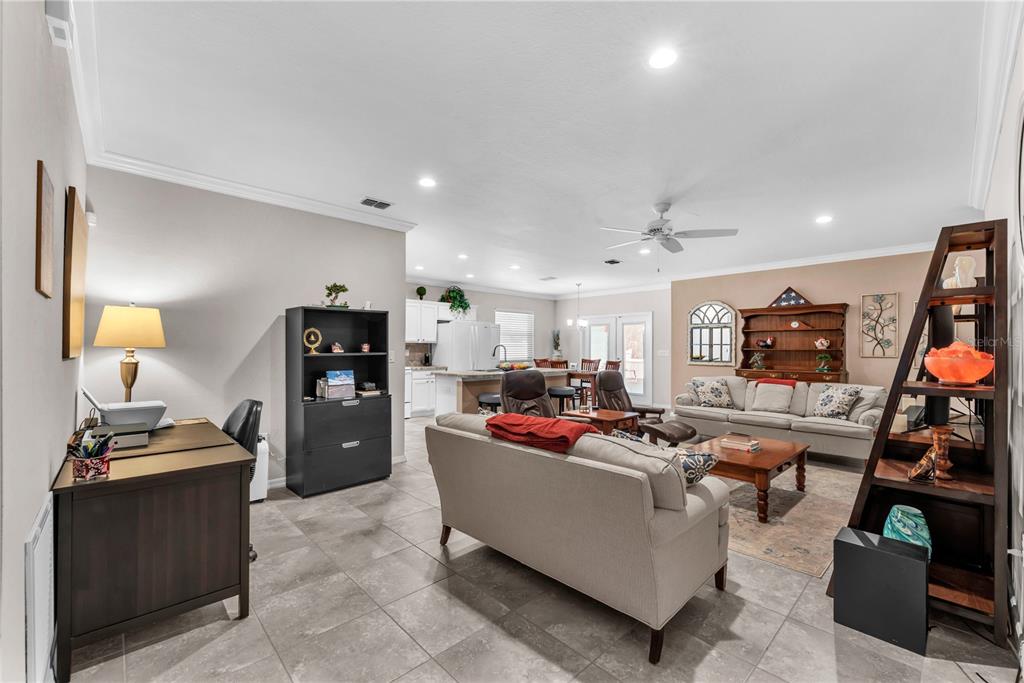 An open-concept living area features a home office, a sofa, and a kitchen in back — 5018 33RD AVENUE E, PALMETTO, FL