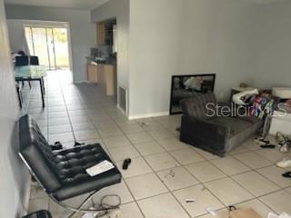 A living room with tiled floors leads to a kitchen and a sliding glass door — 365 S NARANJA AVENUE, PORT ST LUCIE, FL