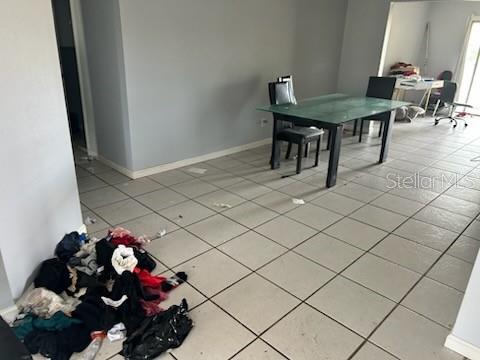 A dining area with a glass table and tile flooring features a pile of laundry — 365 S NARANJA AVENUE, PORT ST LUCIE, FL