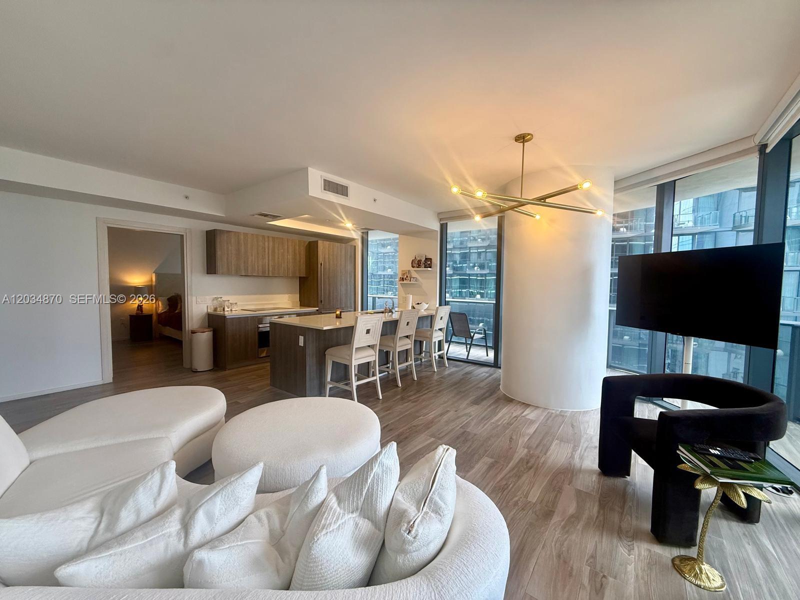 A modern open-concept living area features a kitchen with wood cabinetry and a white island — 801 S Miami Ave # 3005, Miami FL 33130, MIAMI, FL