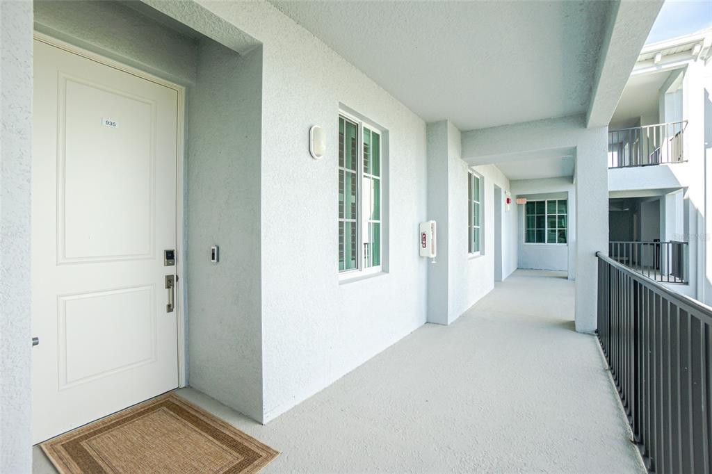 A white apartment door with a welcome mat sits on an outdoor concrete walkway — 14141 HERITAGE LANDING BOULEVARD UNIT 935, PUNTA GORDA, FL