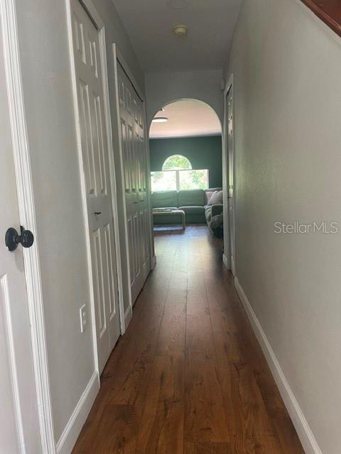 A hallway with wood-look flooring leads to an arched doorway opening into a living room — 114 GLEASON COVE, SANFORD, FL