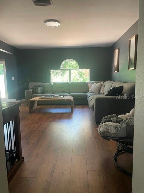 A living room features a large sectional sofa, wood-look flooring, and a central arched window — 114 GLEASON COVE, SANFORD, FL