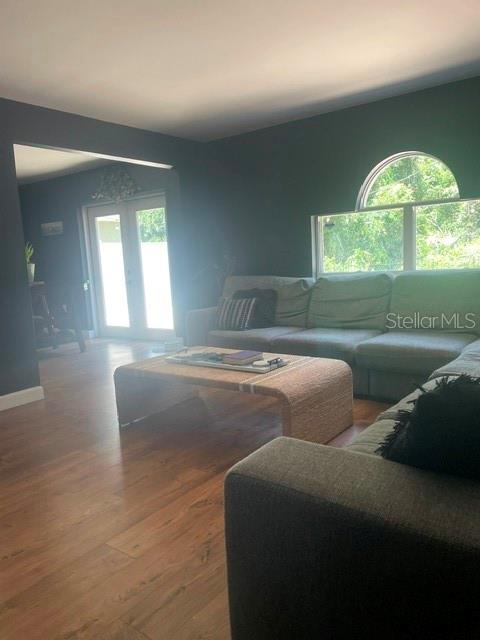A living room with dark walls, wood-look flooring, a sectional sofa, and an arched window — 114 GLEASON COVE, SANFORD, FL