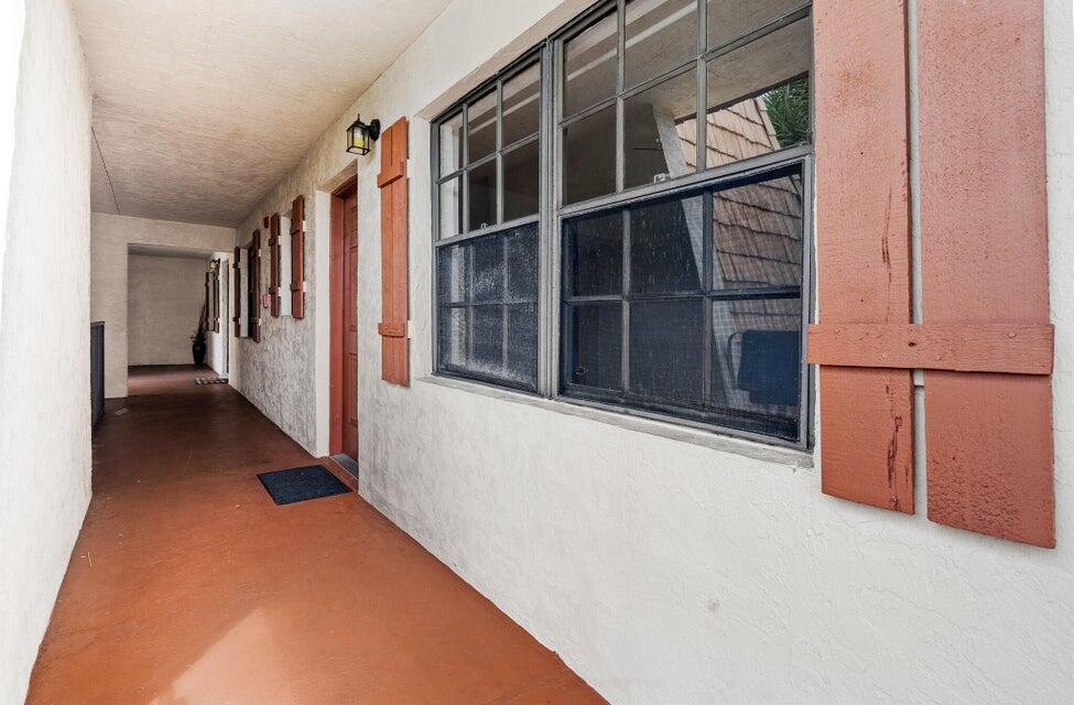 An exterior walkway with a red floor leads to a brown door and window shutters — 4151 Oak Terrace Drive # 4151, FL 33463, FL