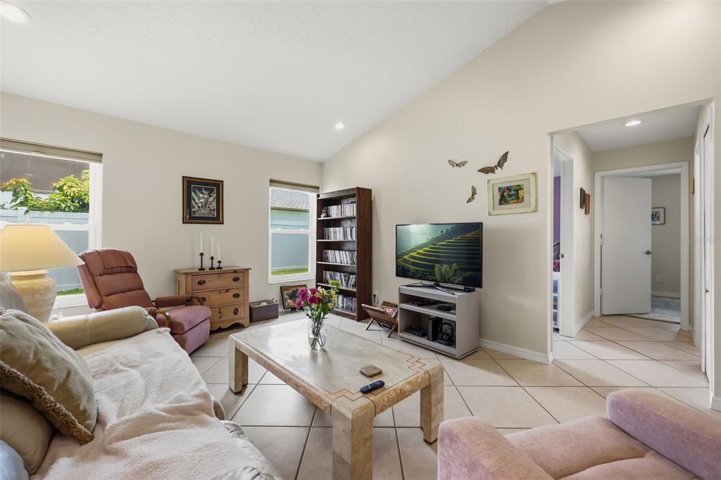 A living room features tile flooring, a vaulted ceiling, a television, and a coffee table — 2427 NOBILITY AVENUE, MELBOURNE, FL