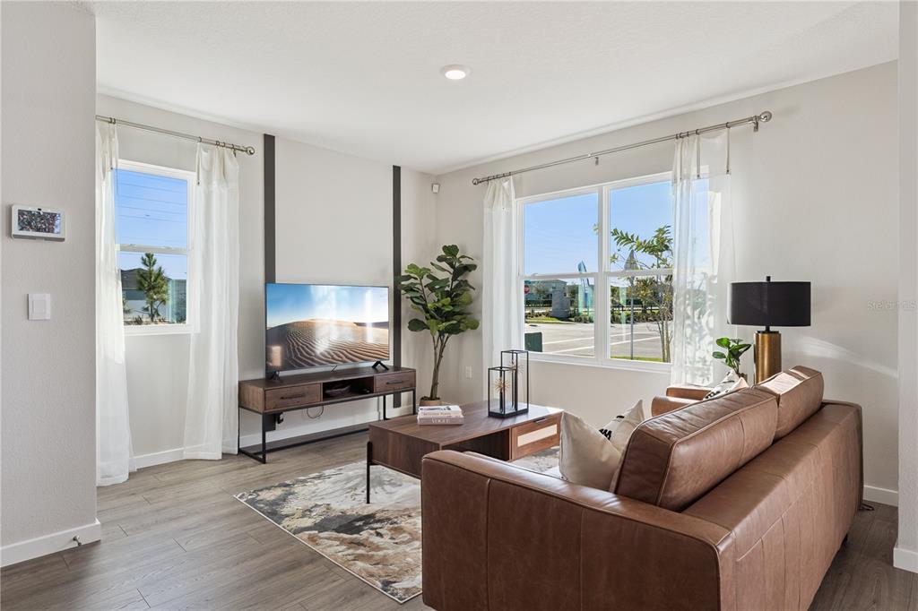 A living room features a brown leather sofa, a television console, and large windows — 592 PRESTON COVE DRIVE, ST CLOUD, FL