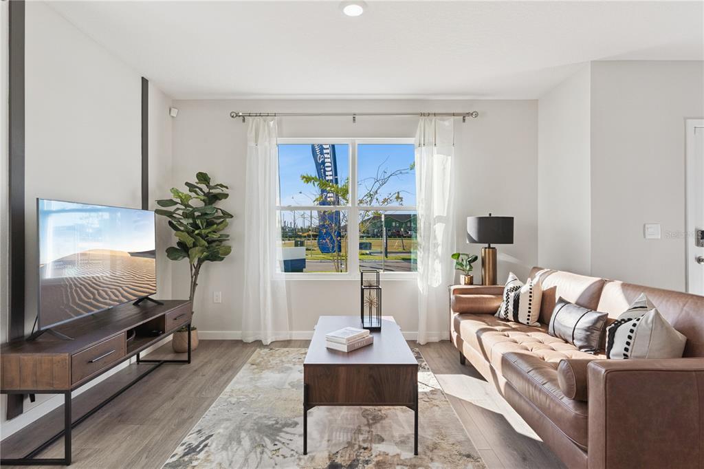 A living room features a brown leather sofa, a wood media console, and a window — 592 PRESTON COVE DRIVE, ST CLOUD, FL