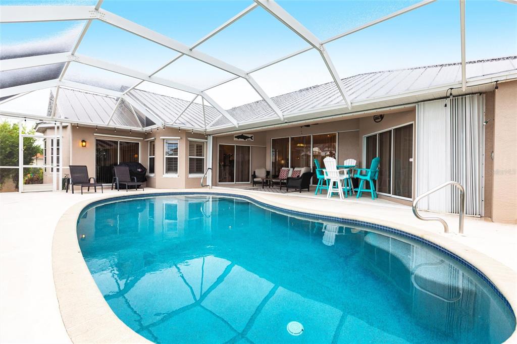 A swimming pool sits on a patio enclosed by a large screened-in lanai structure — 1503 SUZI STREET, PUNTA GORDA, FL