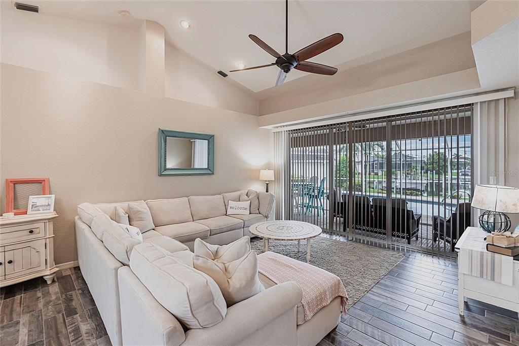 A living room features a large sectional sofa, vaulted ceilings, and sliding glass doors — 1503 SUZI STREET, PUNTA GORDA, FL
