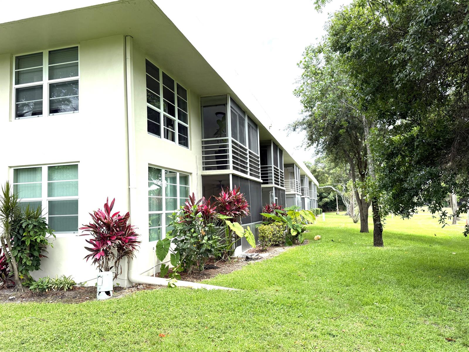 A two-story apartment building with screened balconies and landscaping on a grassy lawn — 907 Cypress Terrace # 201, Pompano Beach FL 33069, POMPANO BEACH, FL