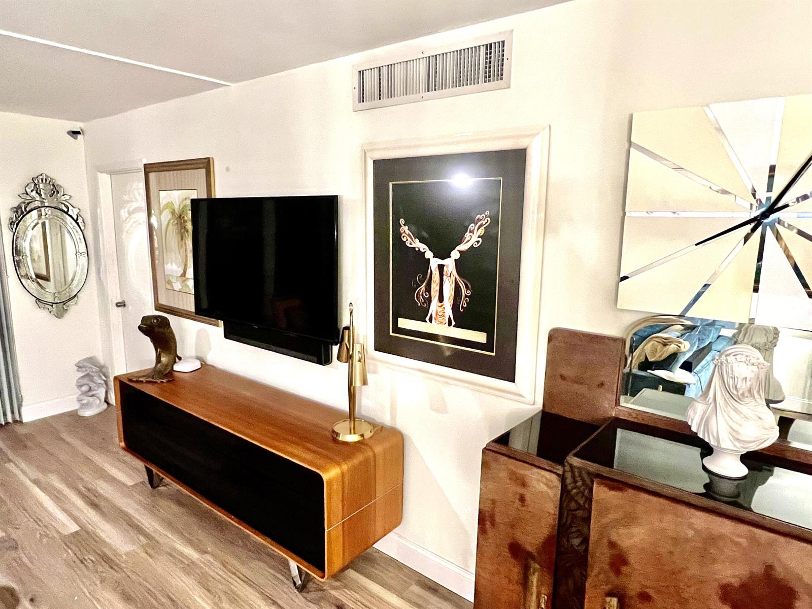 A living room features a wooden media console, a wall-mounted television, and decorative wall art — 907 Cypress Terrace # 201, Pompano Beach FL 33069, POMPANO BEACH, FL