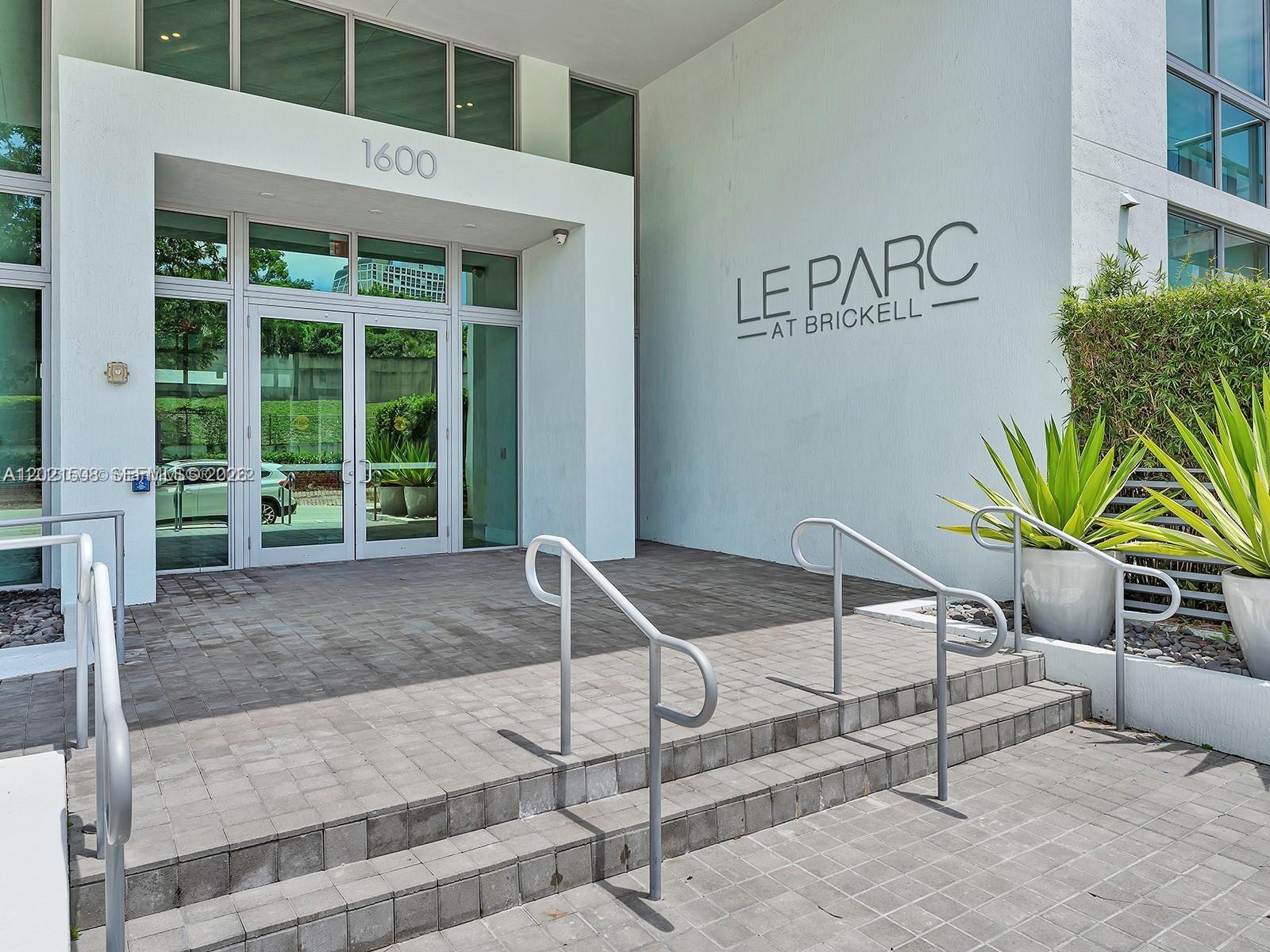 The entrance to a modern building features glass doors, concrete steps, and metal handrails — 1600 SW 1 AVE # 515, Miami FL 33129, MIAMI, FL
