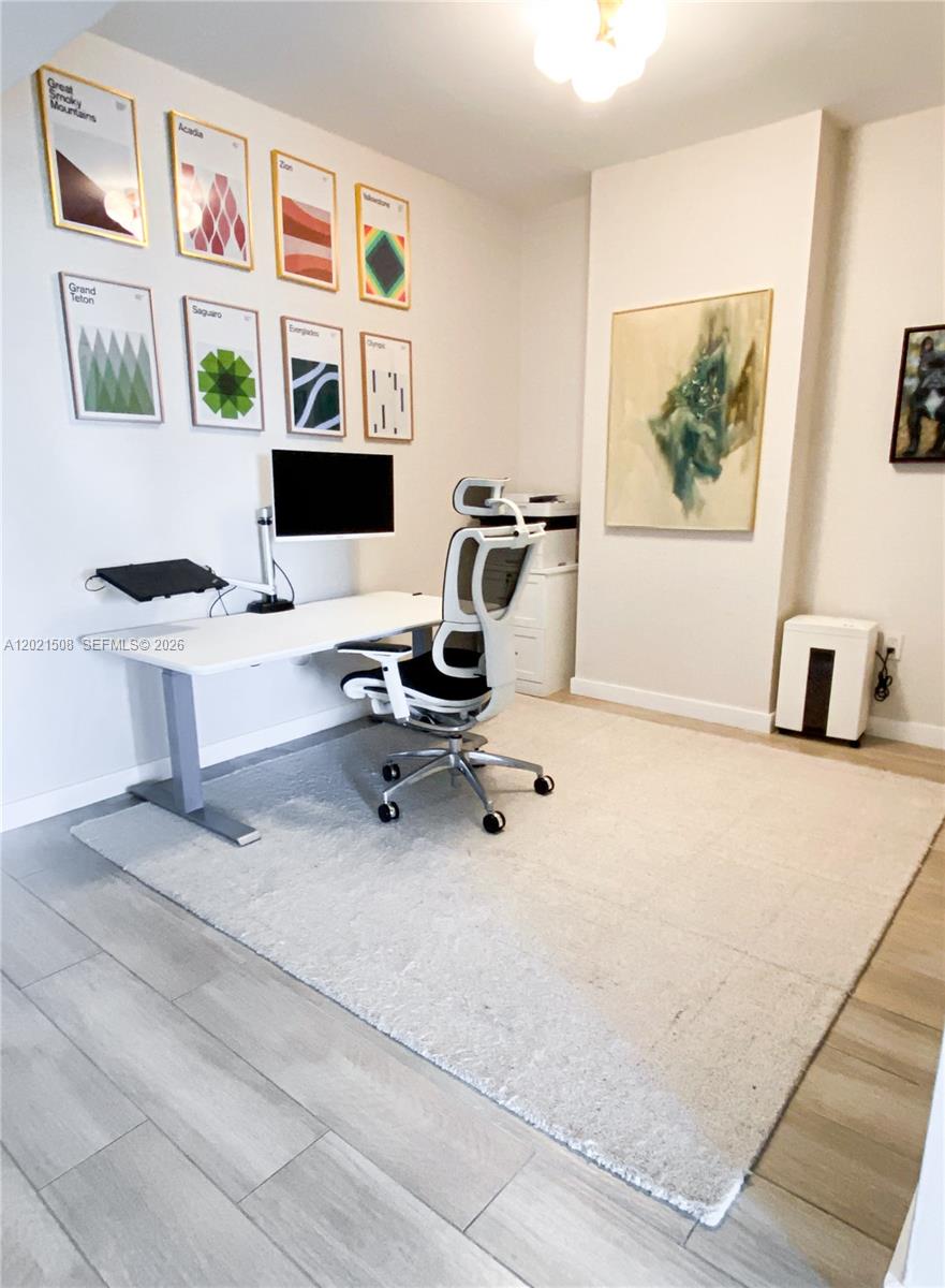 A home office features a white desk, an ergonomic chair, and wall-mounted national park posters — 1600 SW 1 AVE # 515, Miami FL 33129, MIAMI, FL