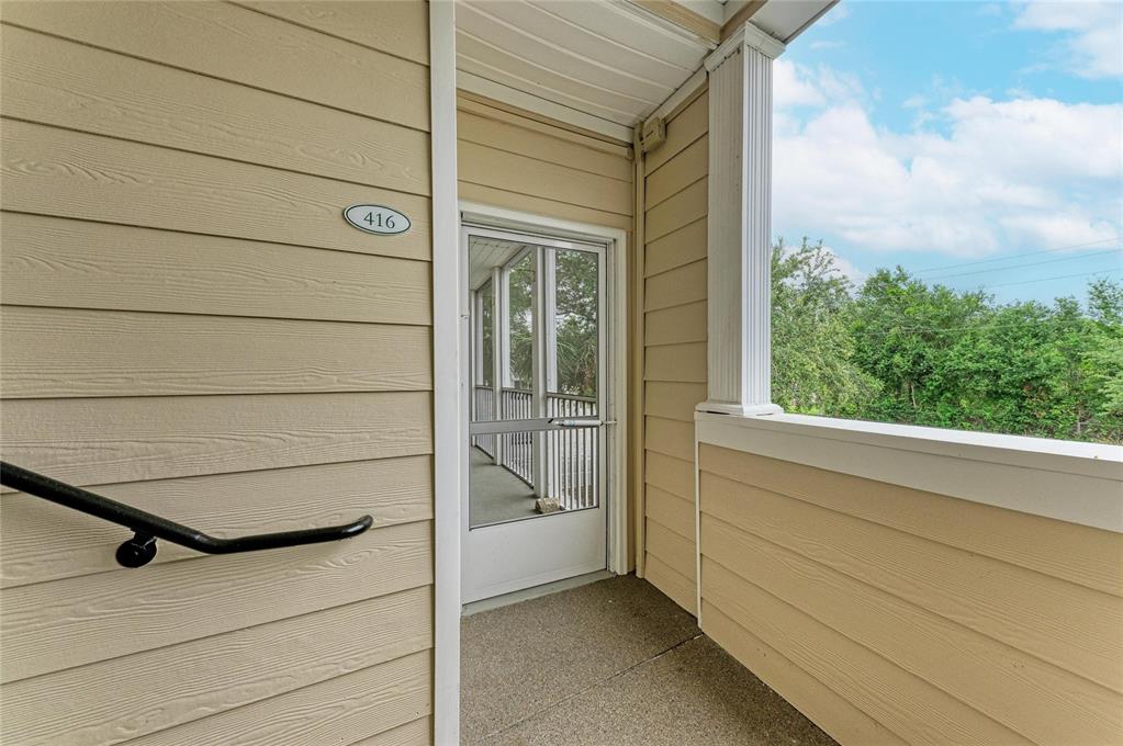 An exterior view of a tan-sided apartment balcony with a screen door labeled 416 — 4802 51ST STREET W UNIT 416, BRADENTON, FL