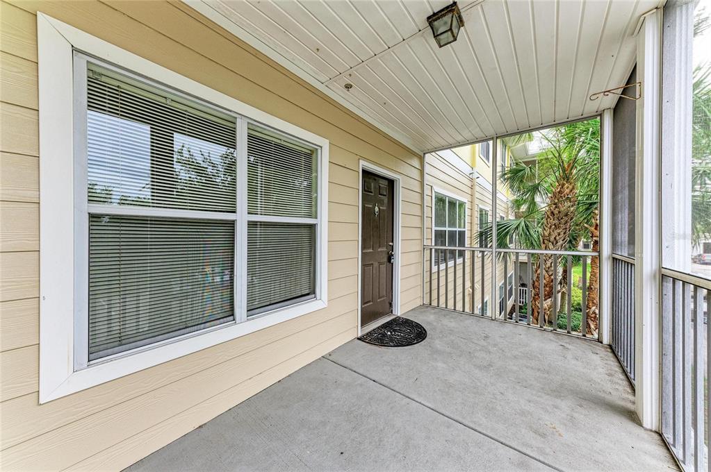 A covered balcony with a concrete floor, a brown door, and a large window — 4802 51ST STREET W UNIT 416, BRADENTON, FL