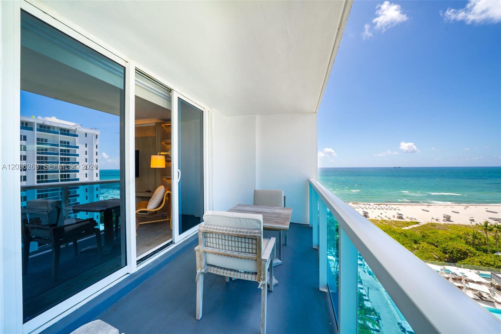 A balcony with outdoor furniture overlooks the ocean and beach from a high-rise building — 102 24th St # 1210, Miami Beach FL 33139, MIAMI BEACH, FL
