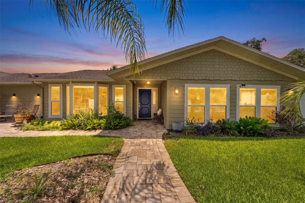 A single-story house with green shingle siding, a blue front door, and a stone walkway — 6355 SEBRING STREET, WEEKI WACHEE, FL