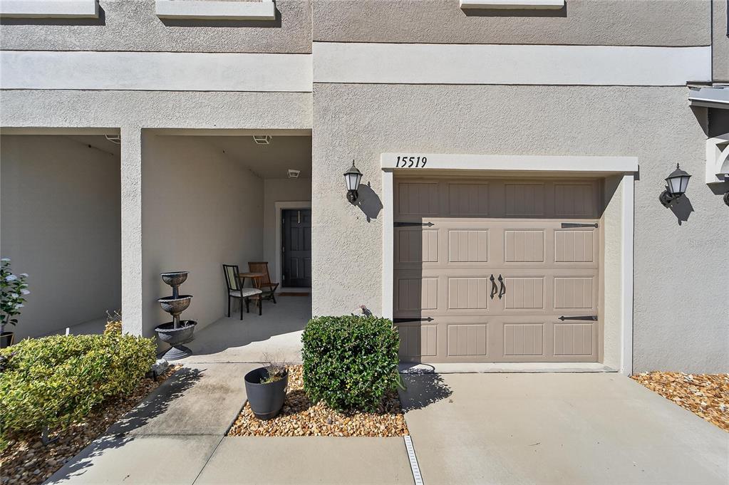 A tan townhouse exterior features a single-car garage, a covered entryway, and a small garden — 15519 PRESTWICK ROSE PLACE, SUN CITY CENTER, FL