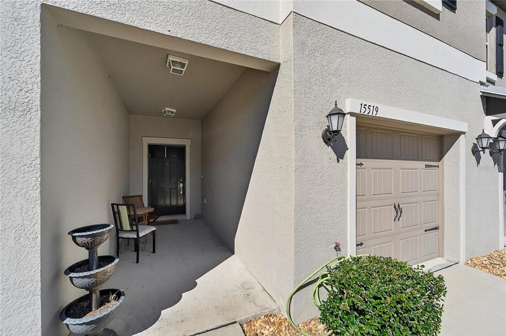 The exterior of a home features a covered entryway, a garage, and a tiered planter — 15519 PRESTWICK ROSE PLACE, SUN CITY CENTER, FL
