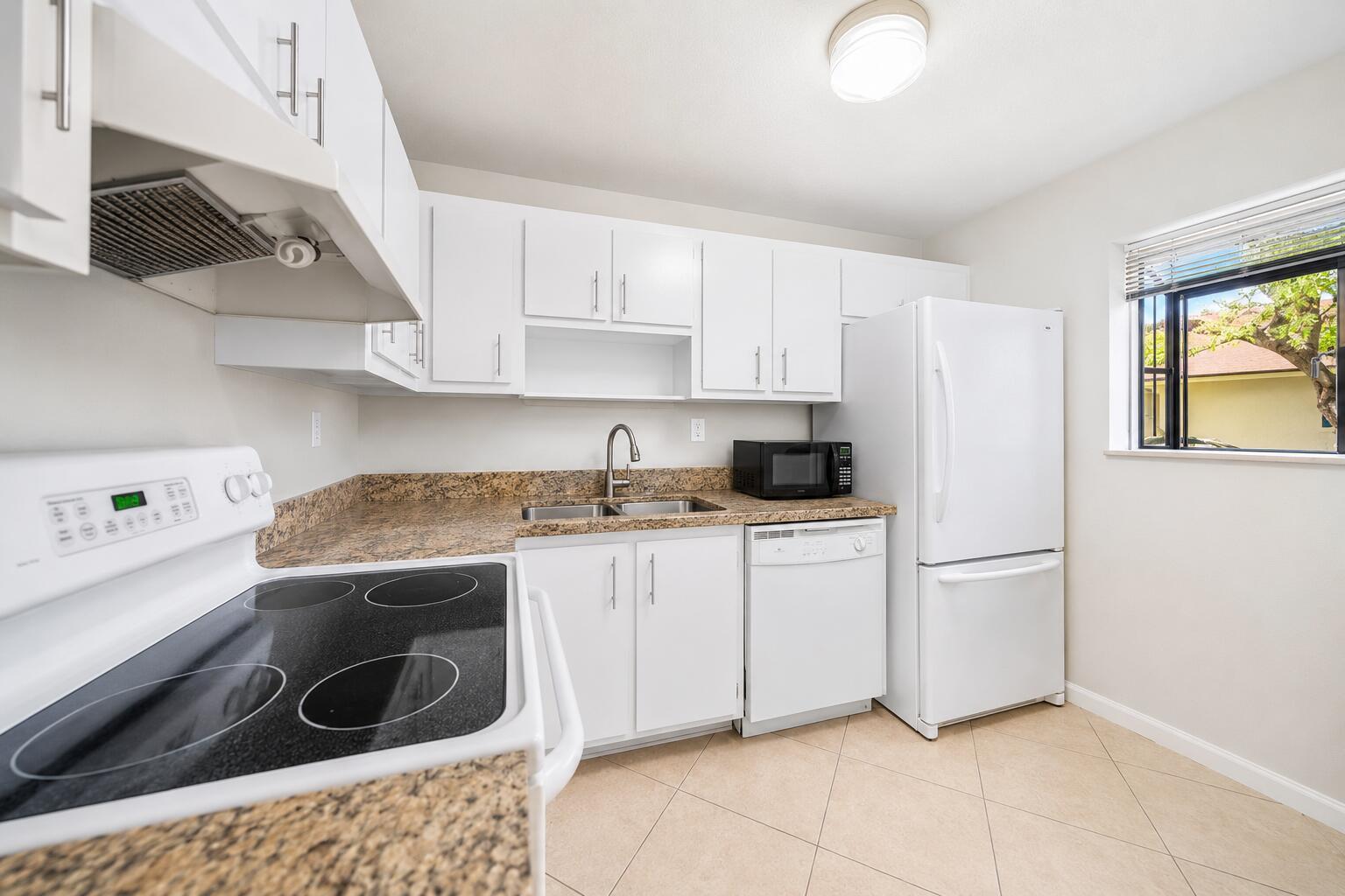 A kitchen features white cabinets, granite countertops, a white stove, and a white refrigerator — 503 Gardens Drive # 202, Pompano Beach FL 33069, POMPANO BEACH, FL
