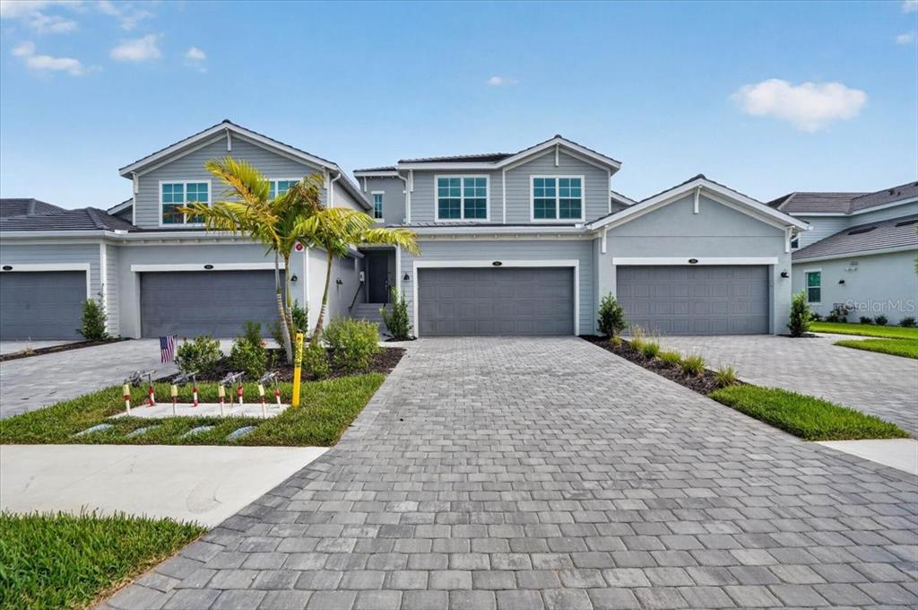 A multi-unit residential building with gray siding, three garage doors, and a paved driveway — 19209 CHERRYSTONE WAY UNIT 103, LAKEWOOD RANCH, FL