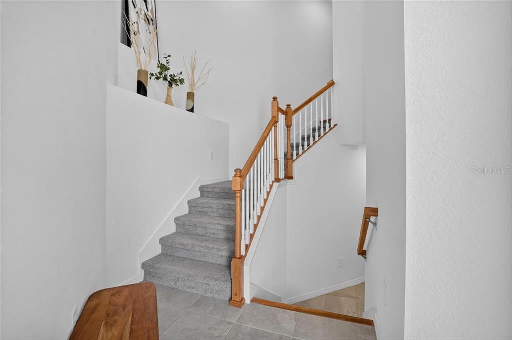 A staircase with carpeted steps and a wooden railing leads to an upper level — 19209 CHERRYSTONE WAY UNIT 103, LAKEWOOD RANCH, FL