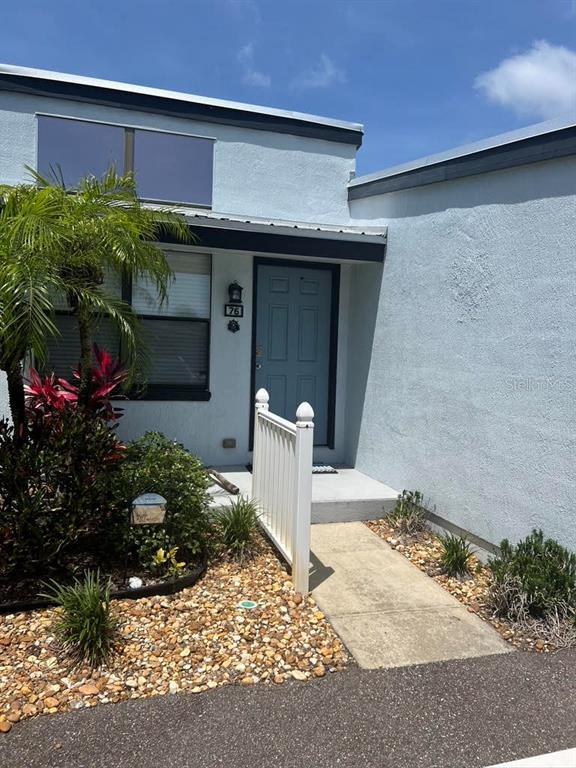 A light blue house exterior features a front door, a white fence, and gravel landscaping — 76 HEATHER POINT COURT, NEW SMYRNA BEACH, FL