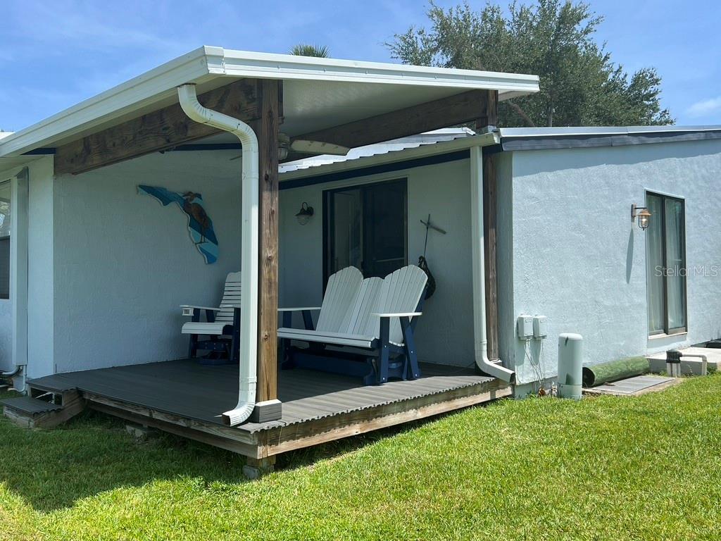 A covered wooden deck with outdoor seating is attached to the side of a house — 76 HEATHER POINT COURT, NEW SMYRNA BEACH, FL