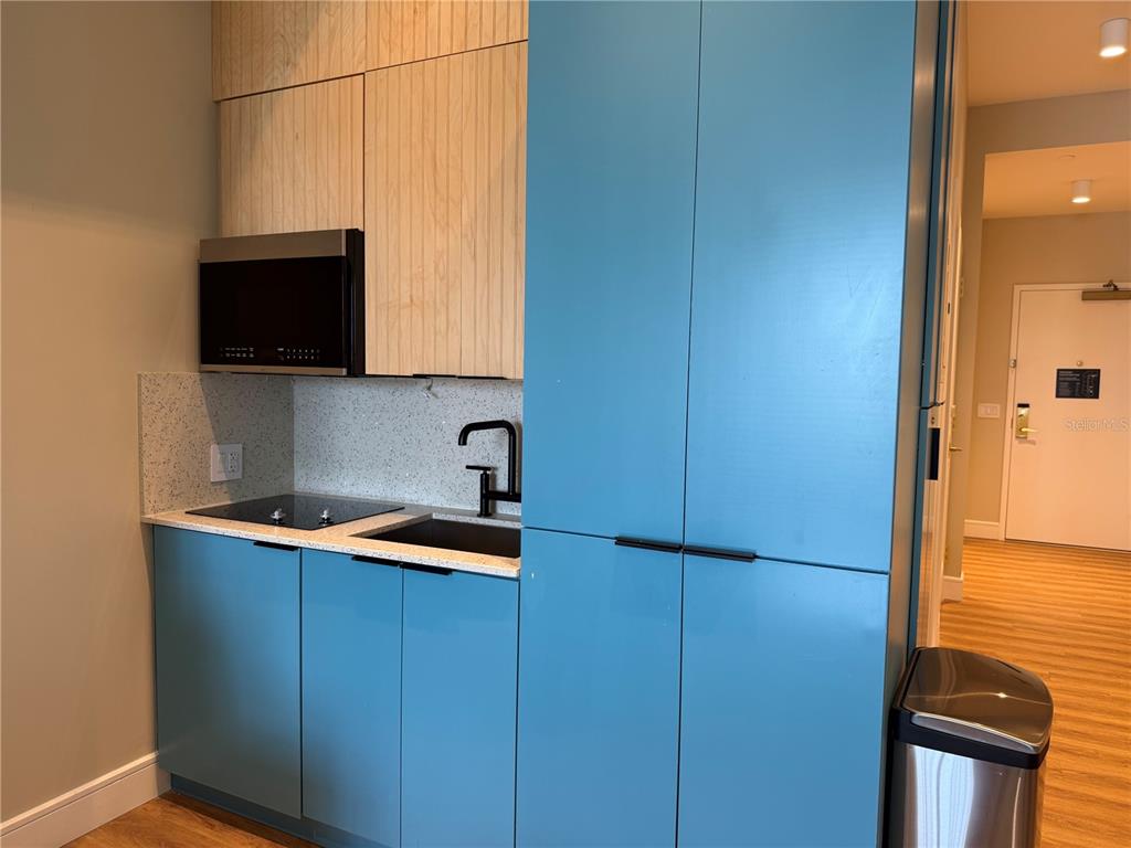 A kitchenette features blue lower cabinets, light wood upper cabinets, and a speckled countertop — 8050 VACATION AVENUE UNIT 302, KISSIMMEE, FL