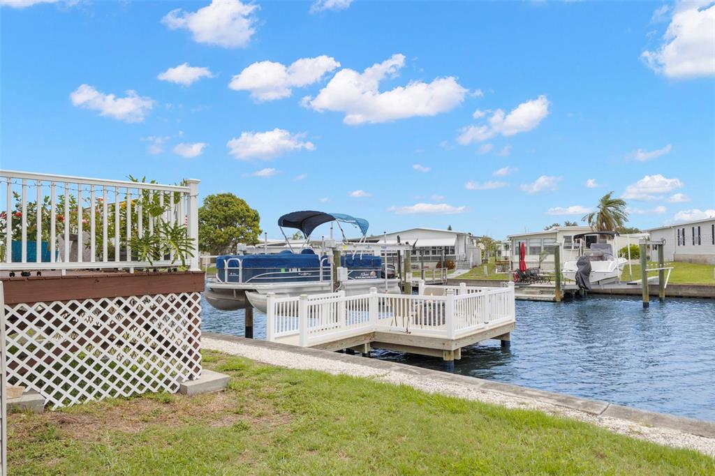 A backyard deck overlooks a canal with a boat lift and a small dock — 124 AMERICANA COURT NE UNIT 214, ST PETERSBURG, FL