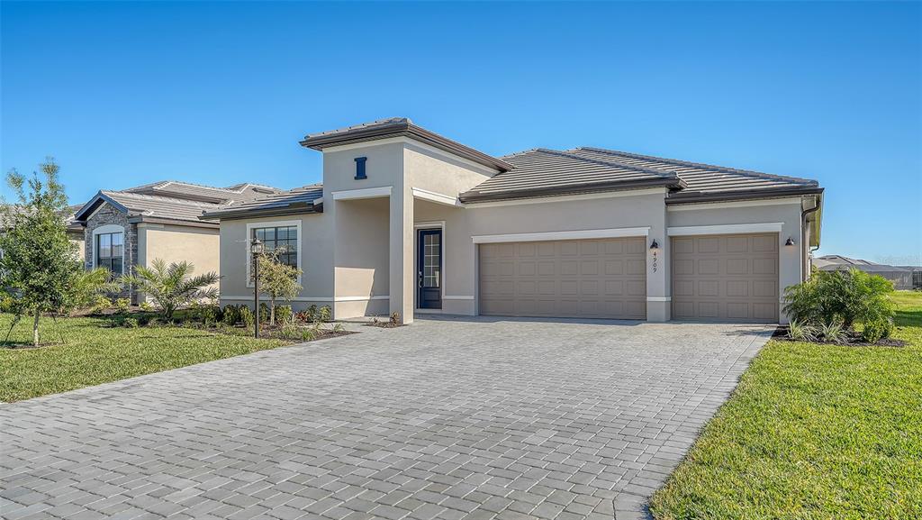 A single-story house with a beige stucco exterior, a tiled roof, and a paved driveway — 4909 OYSTER PEARL STREET, LAKEWOOD RANCH, FL