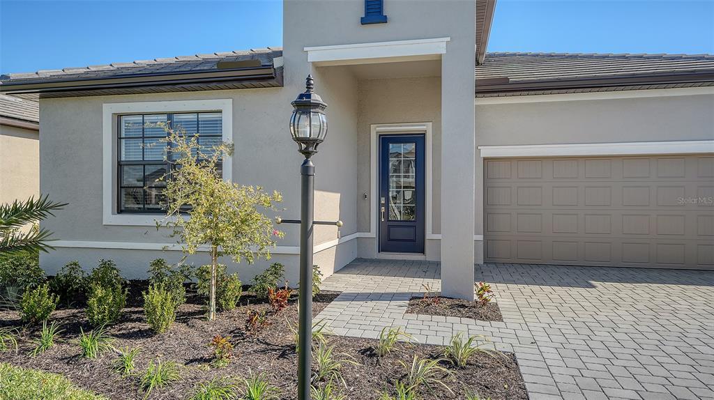 The exterior of a house features a paved driveway, a dark front door, and landscaping — 4909 OYSTER PEARL STREET, LAKEWOOD RANCH, FL