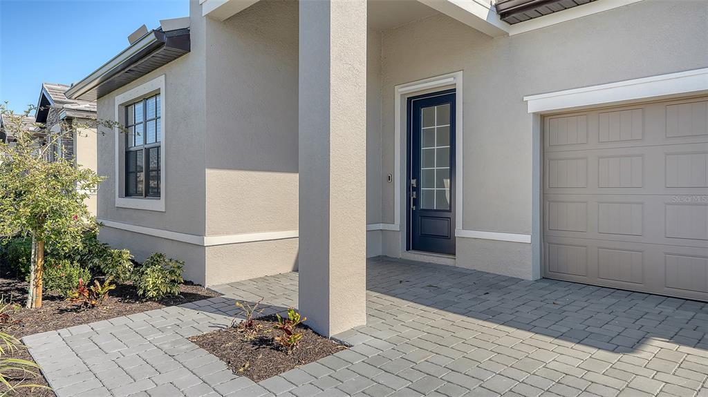 A paved walkway leads to the front entrance of a house with a beige garage — 4909 OYSTER PEARL STREET, LAKEWOOD RANCH, FL