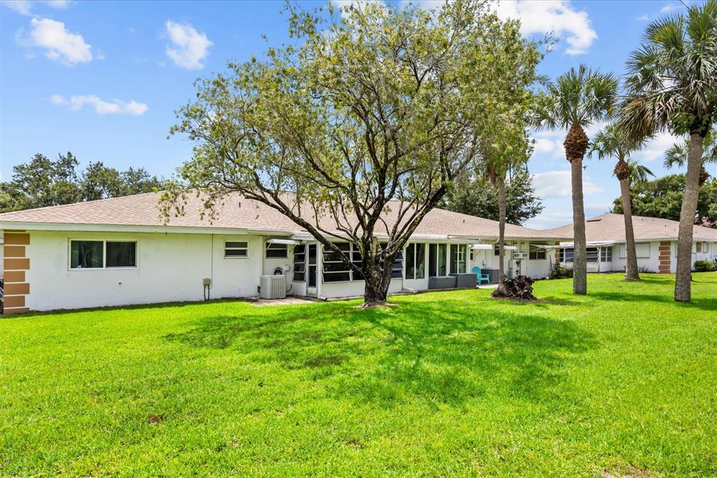 A white single-story house with a large tree in the backyard and several palm trees — 127 LAKES END DRIVE UNIT C, FORT PIERCE, FL